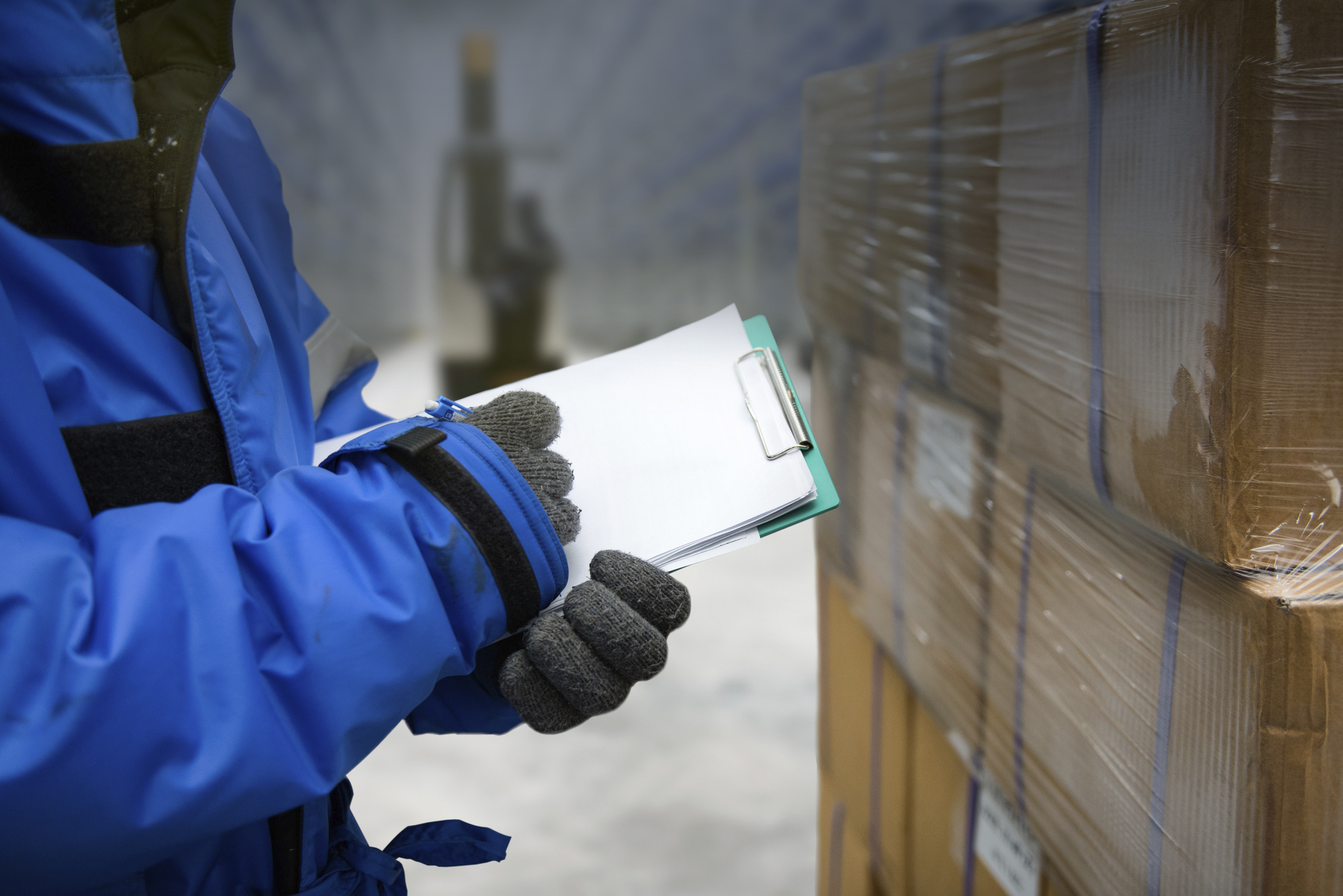 Closeup shooting hand of worker with clipboard checking goods in